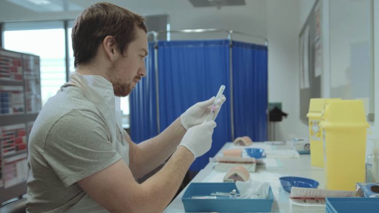 Lewis Oliva preparing a syringe in a medical training room at the University Hospital of Wales, Cardiff